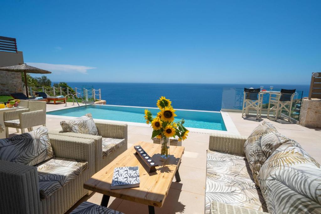 斯卡拉Tsimaras Villas的天井配有沙发和带向日葵的桌子。