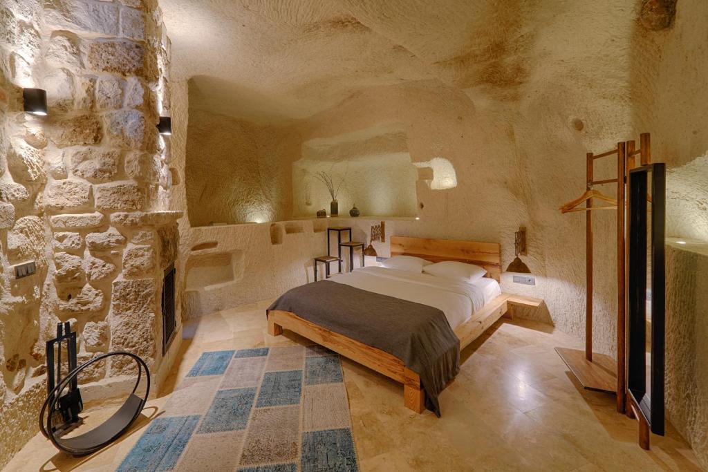 格雷梅Luvi Cave Hotel的一间卧室设有一张床和石墙