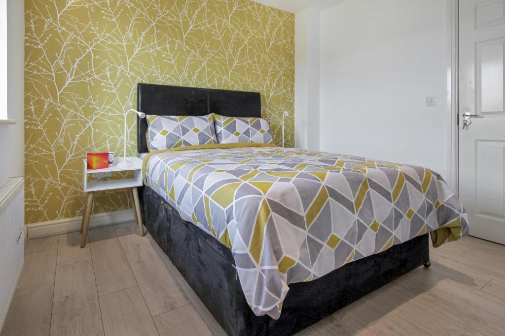 德比Emerald En-suite in Derby的一间卧室配有一张黄色和灰色的被子。