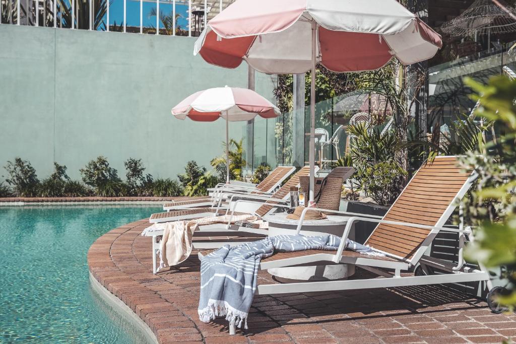 黄金海岸黄金海岸小岛酒店的游泳池旁的一排椅子和遮阳伞