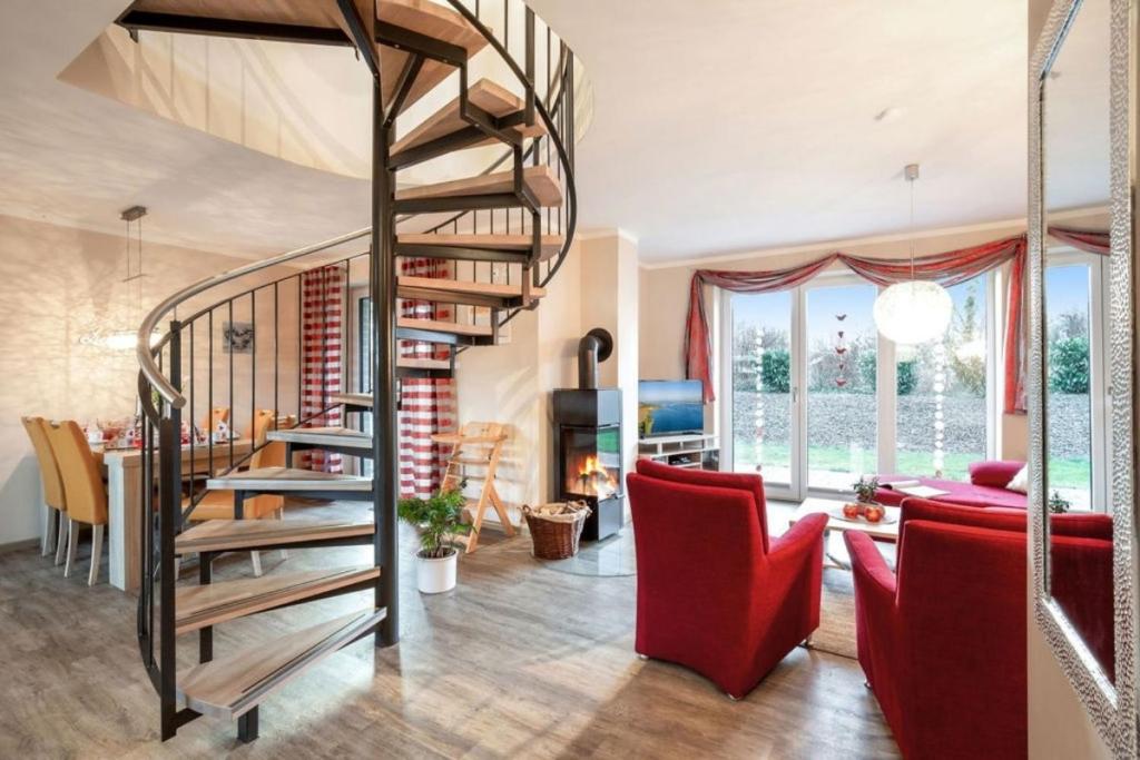 KlausdorfWellness - Ferienhaus Küstenwind的客厅设有螺旋楼梯和红色椅子