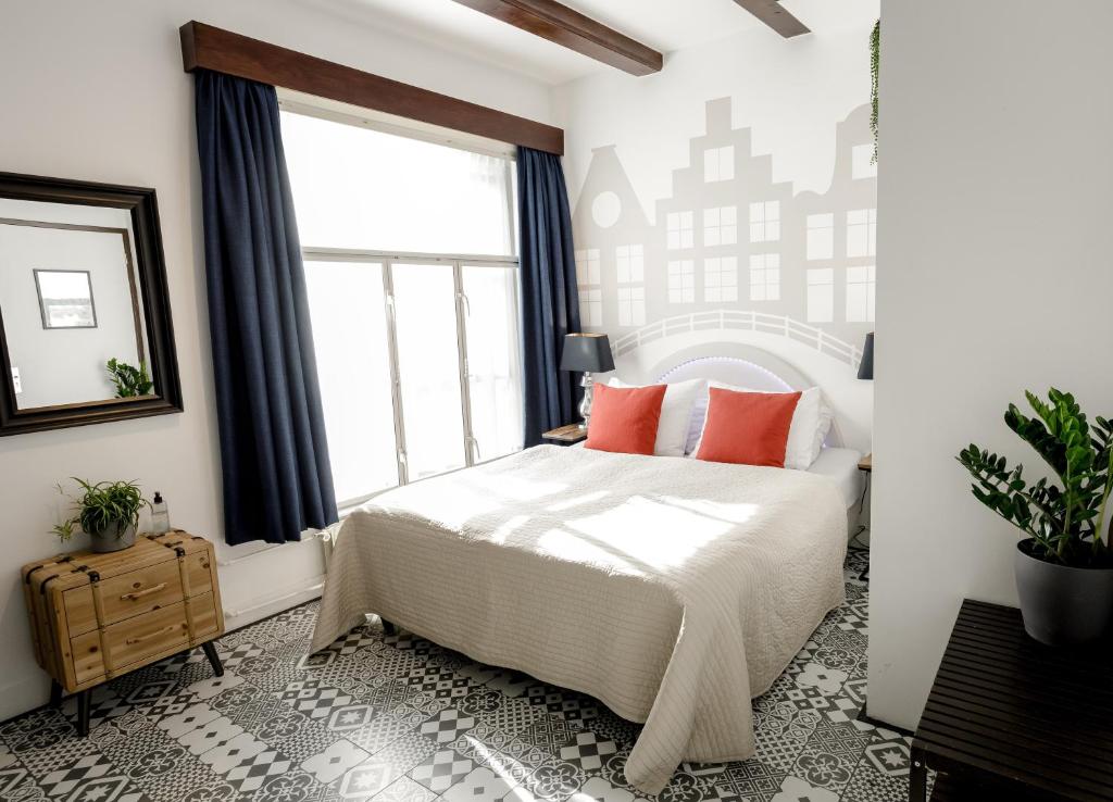 阿姆斯特丹Aris Amsterdam的一间卧室配有带橙色枕头的床和窗户。