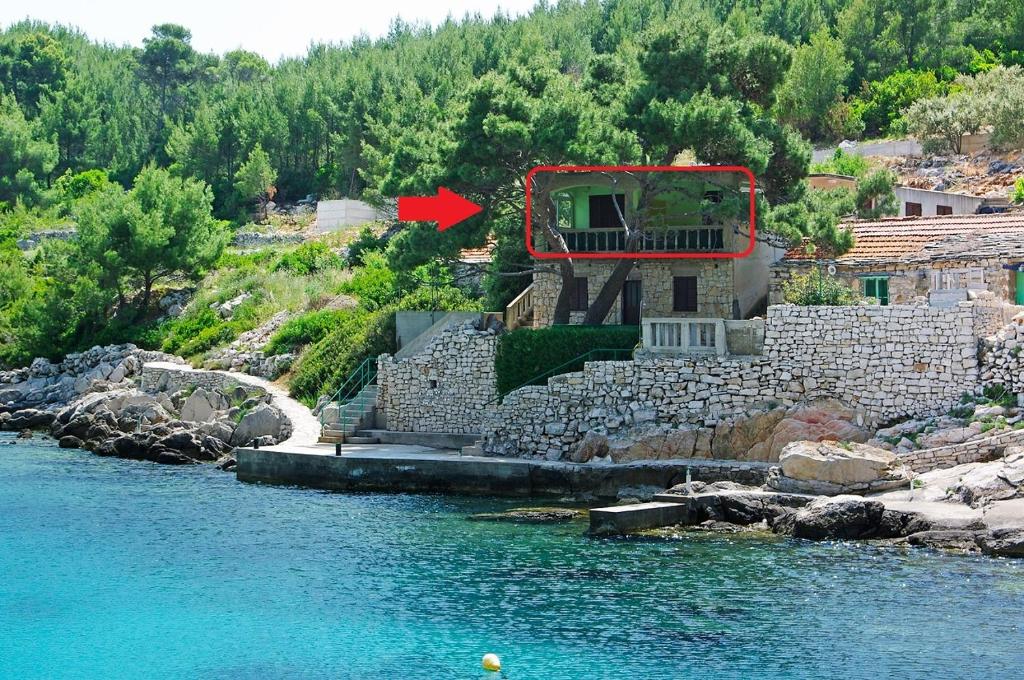 普利兹巴Guesthouse Karbuni (217)的河岸边的一座房子,有红箭