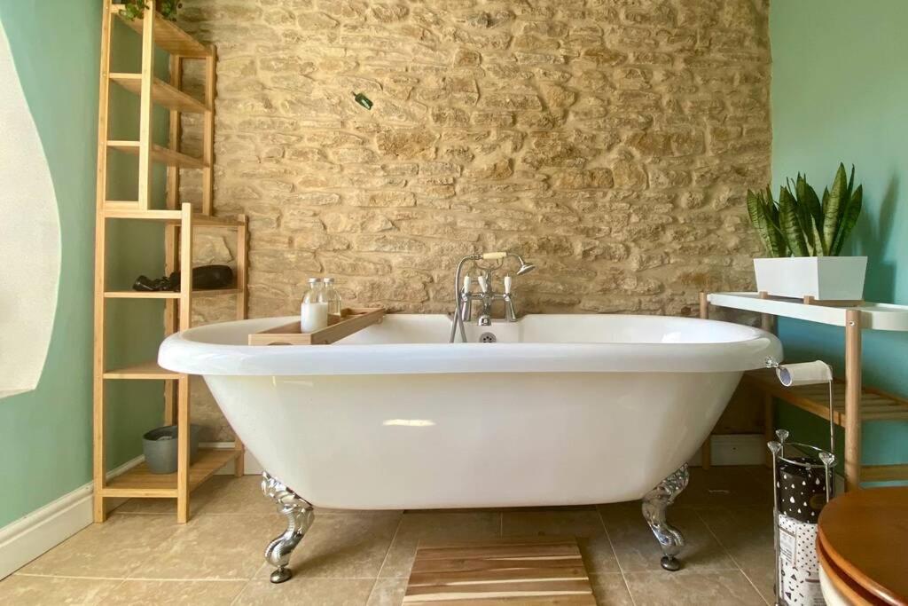 Buckland DinhamThe Explorers Rest - Cottage - Frome的石墙浴室内的白色浴缸