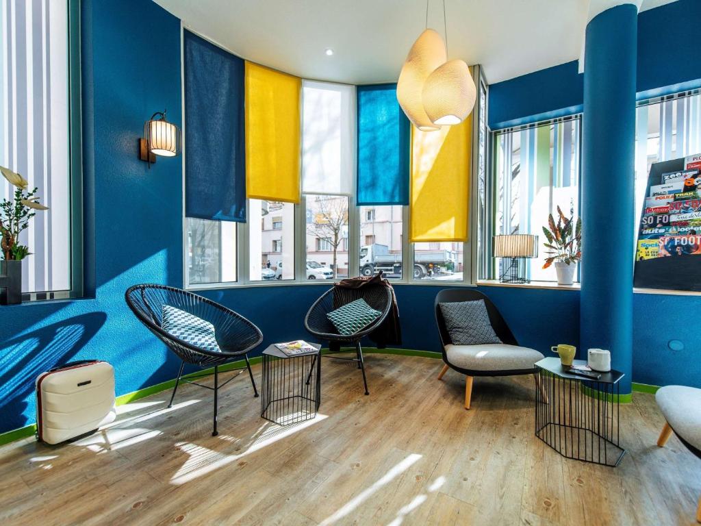 里昂Ibis Styles Lyon Croix Rousse的配有椅子和蓝色墙壁及窗户的房间