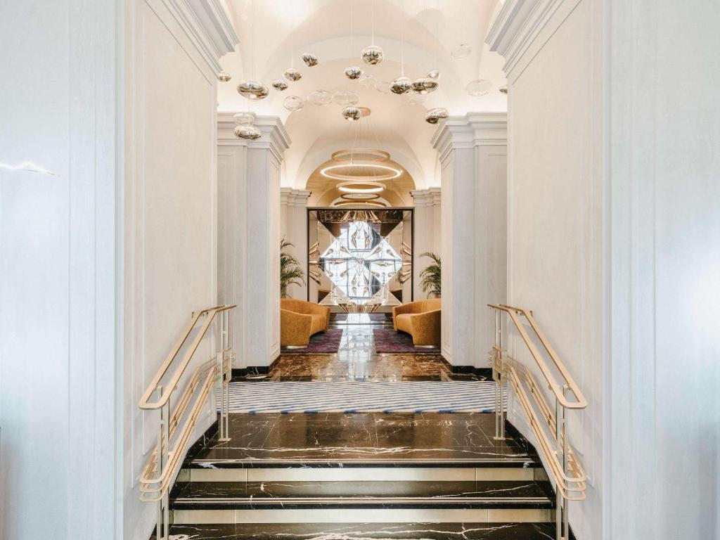 华沙莱佛士欧罗佩斯基华沙酒店的通往大堂的楼梯,配有吊灯