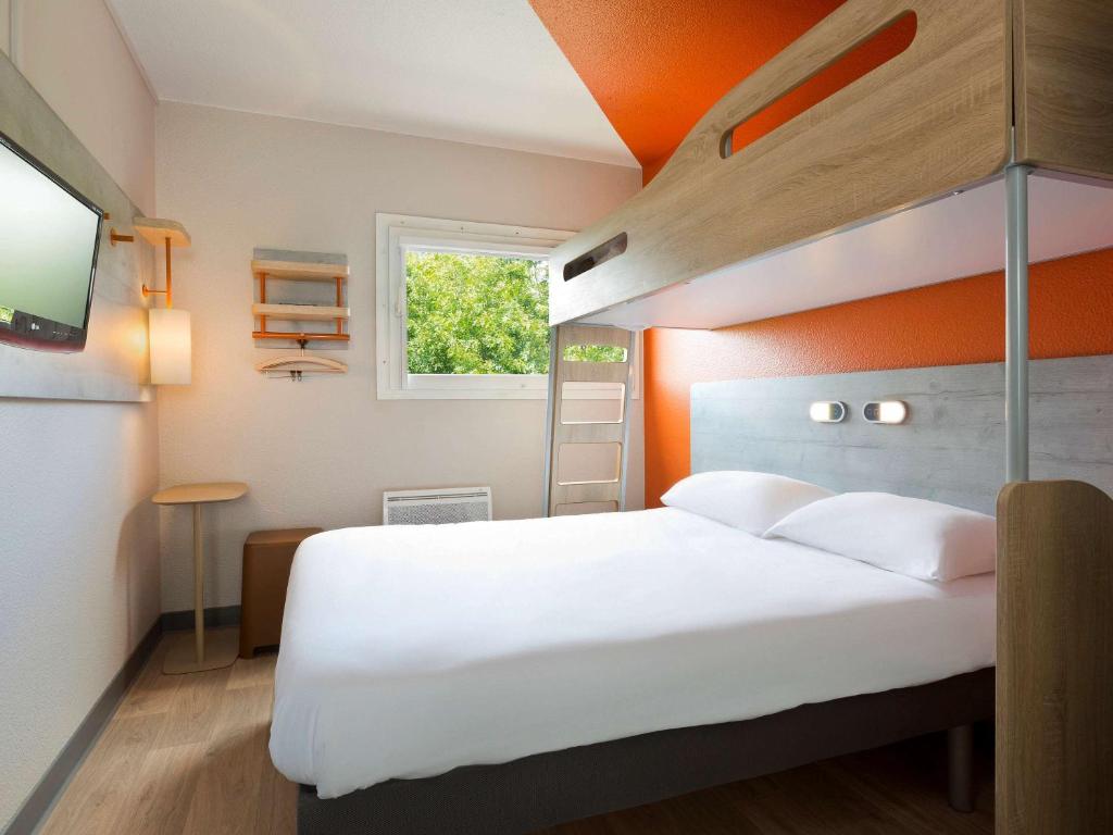 勒芒ibis budget Le Mans Universite的卧室配有白色的床和橙色的墙壁