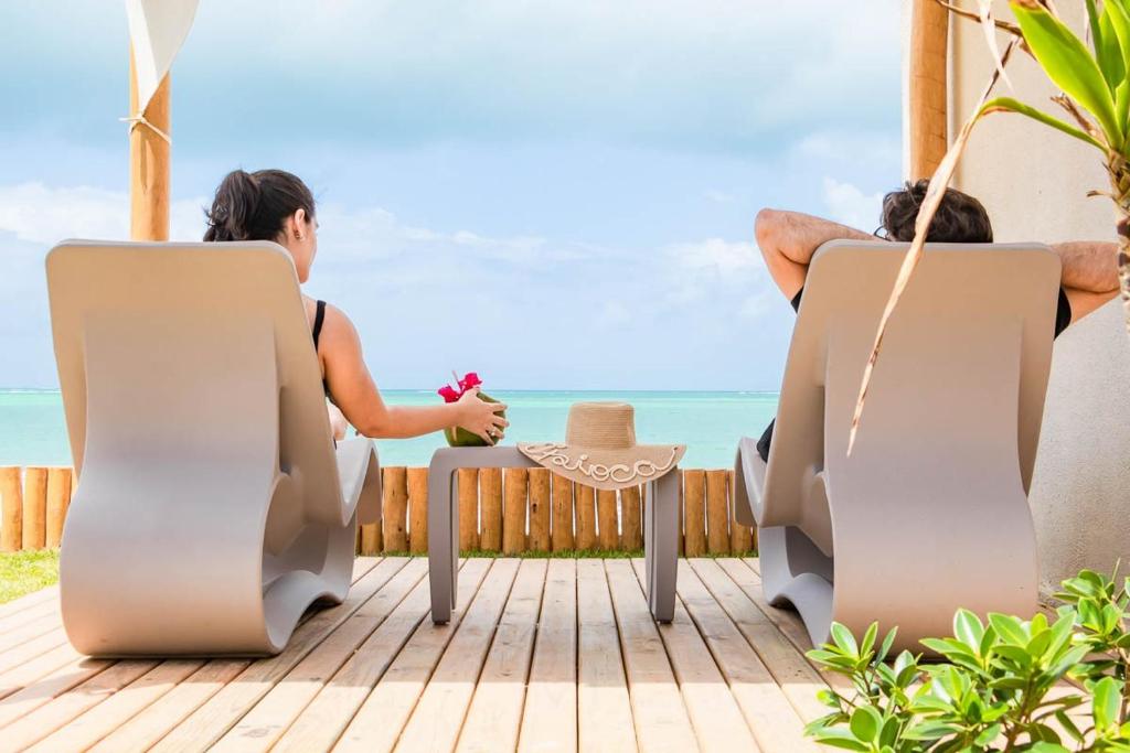 马塞约Wave Suítes Hotel & Lounge bar的两个人坐在甲板上,眺望着大海