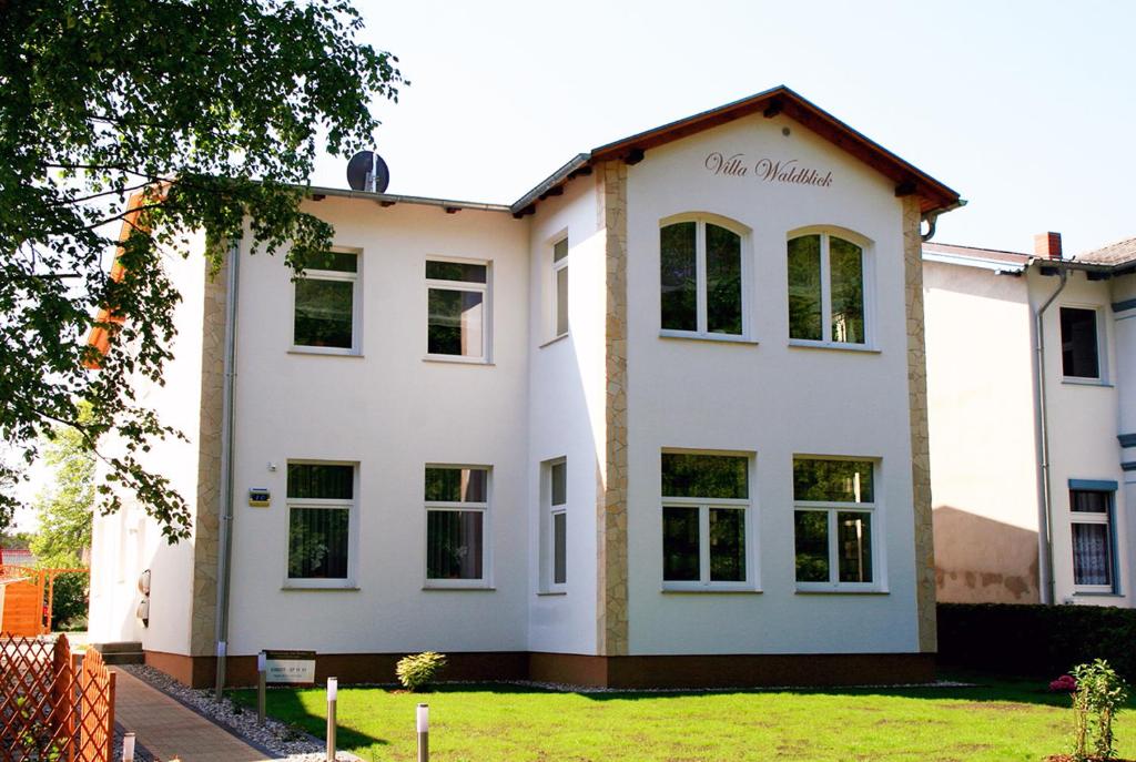 岑平Ferienwohnungen Villa Waldblick的白色的建筑,上面有标志