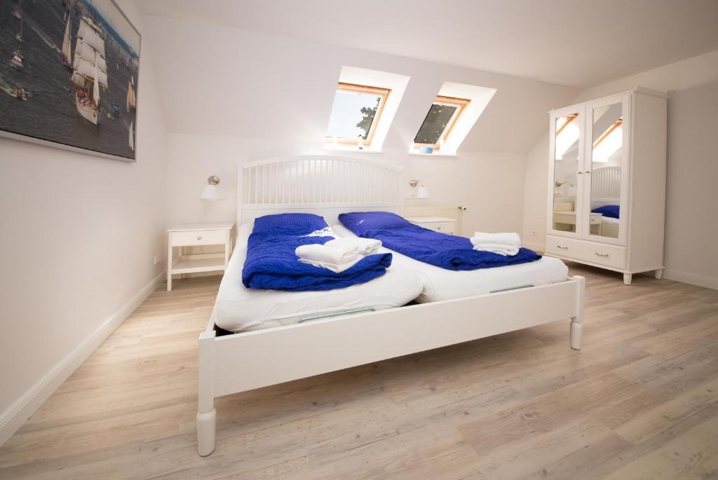拉本基尔兴-福吕克Schleiblick App 18的一间卧室配有白色的床和蓝色的毯子