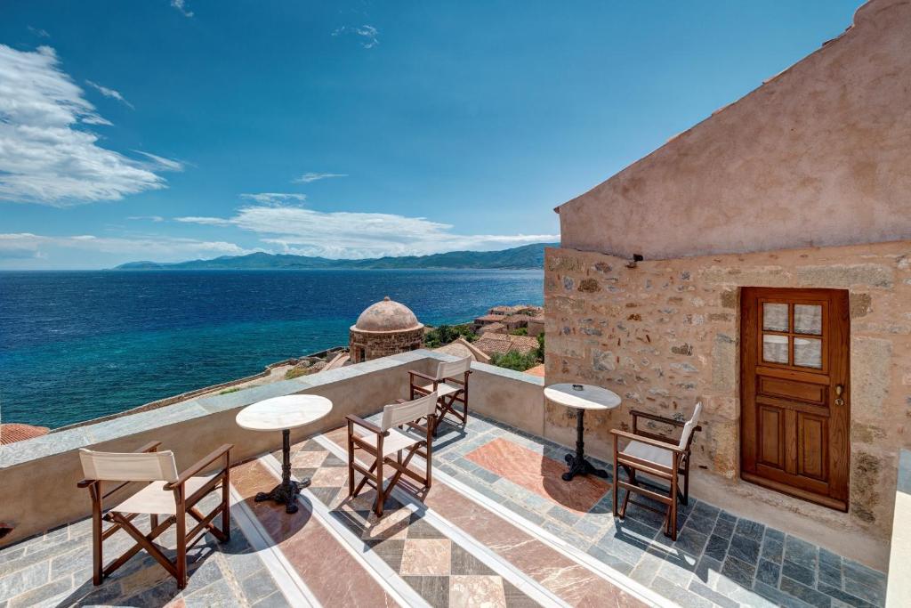 莫奈姆瓦夏玛尔维萨传统酒店的一个带桌椅的庭院,俯瞰着大海
