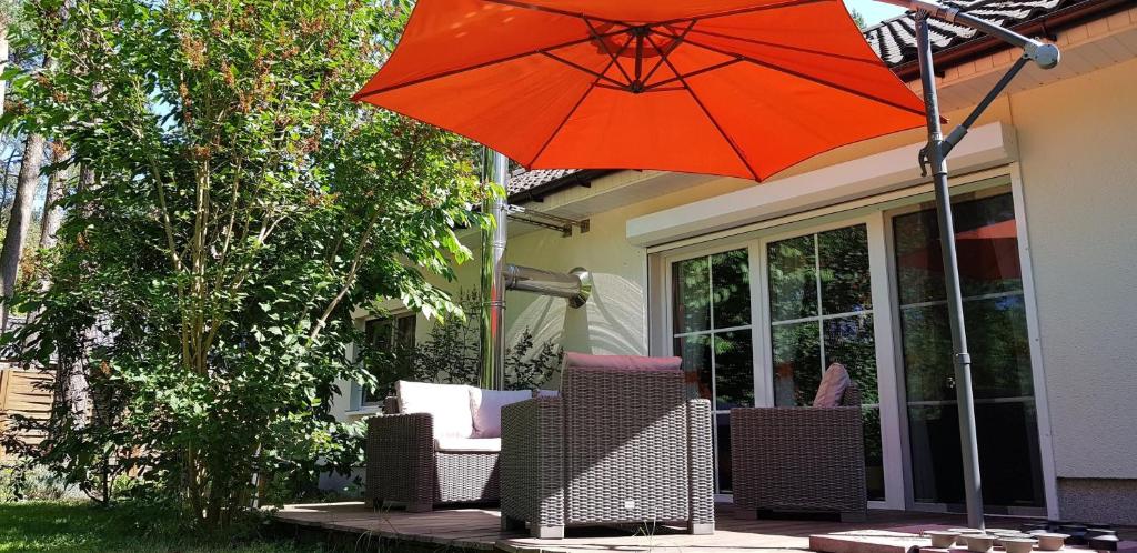 贝利茨Ferienhaus Fichtenwalde的一把橙色遮阳伞,坐在带椅子的庭院