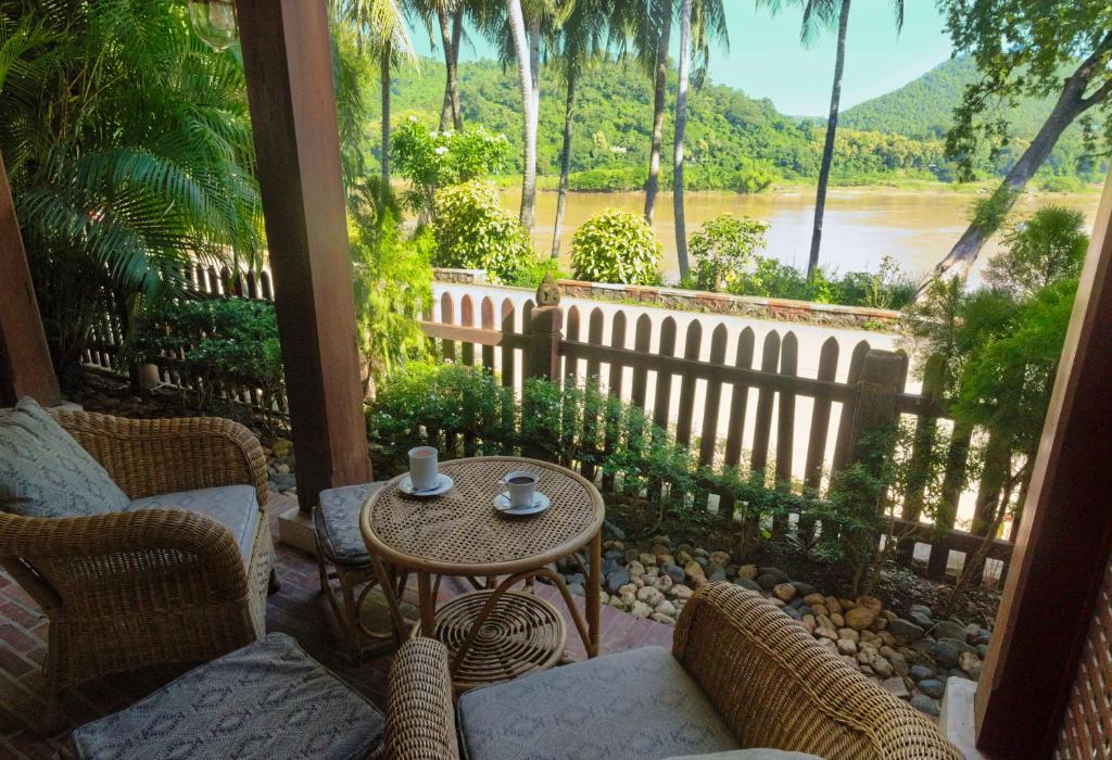 琅勃拉邦湄公河景观酒店的河景门廊配有桌椅