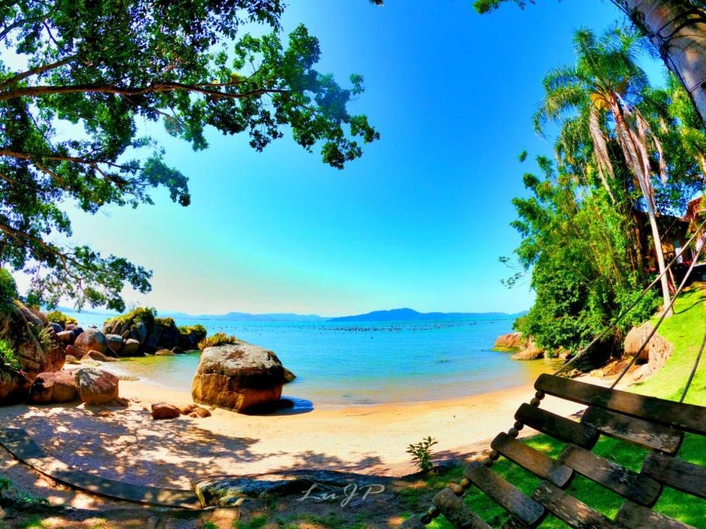 塞尔苏拉穆斯州长镇Villa dos Ganchos的海滩上拥有长凳、水和树木