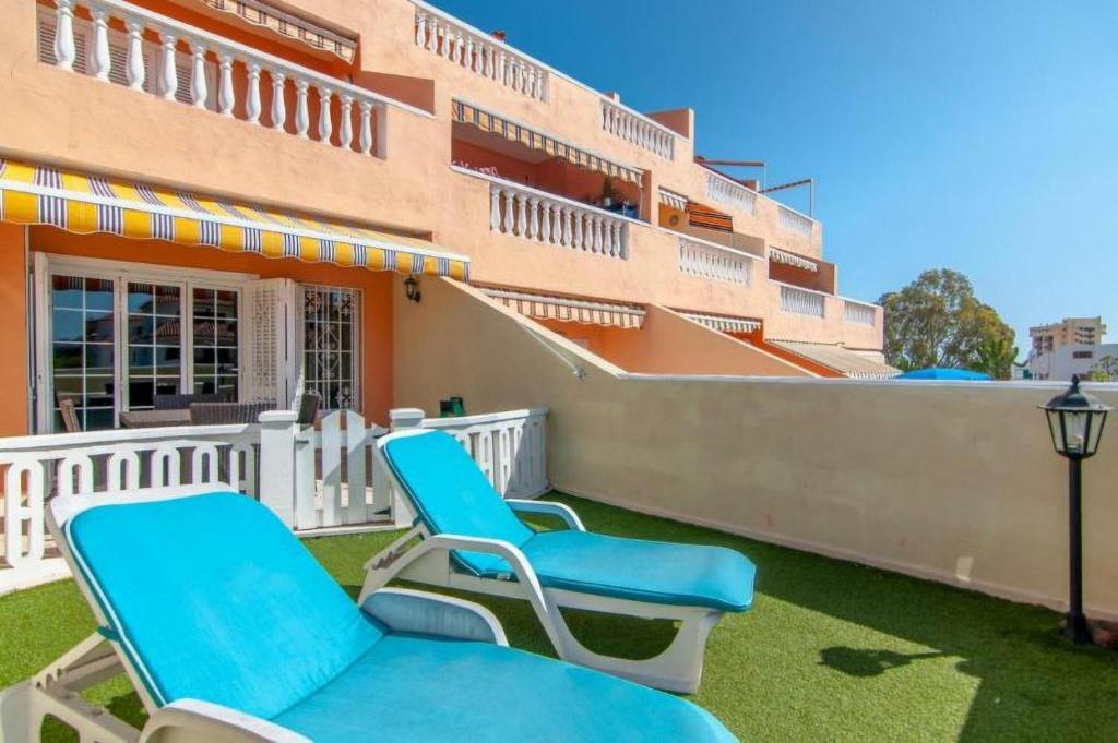 洛斯克里斯蒂亚诺斯Apartament 1 bedroom Los Cristianos Las Vistas beach的坐在大楼前的庭院里的一对椅子