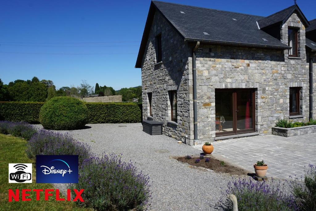 杜柏Gîte du Vieux Chemin的石头房子,带紫色花的庭院