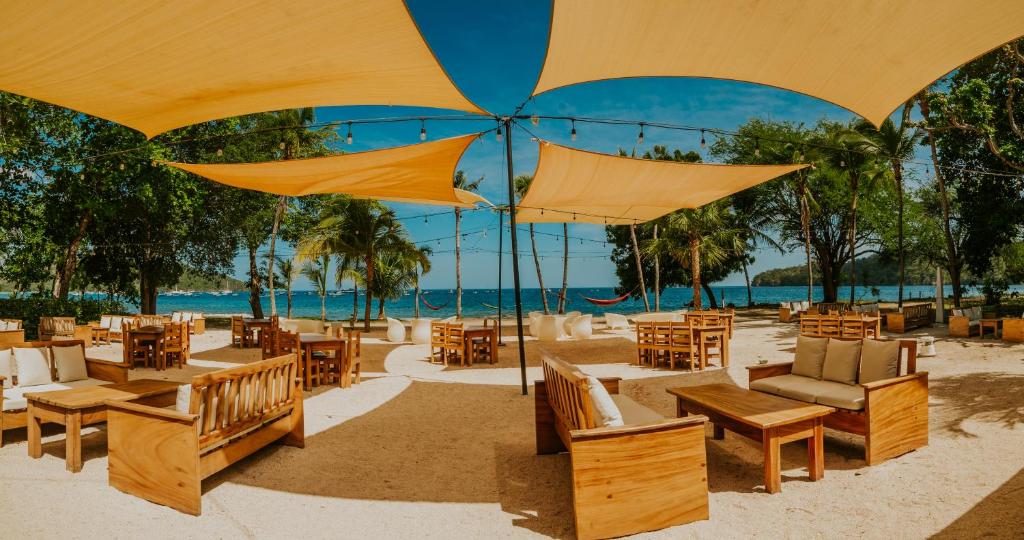 科克Café de Playa Beach Front Hotel的一个带桌椅和遮阳伞的海滩