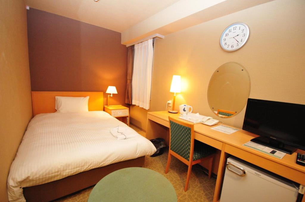 仙台高级绿丘酒店的配有一张床、一张桌子和闹钟的酒店客房