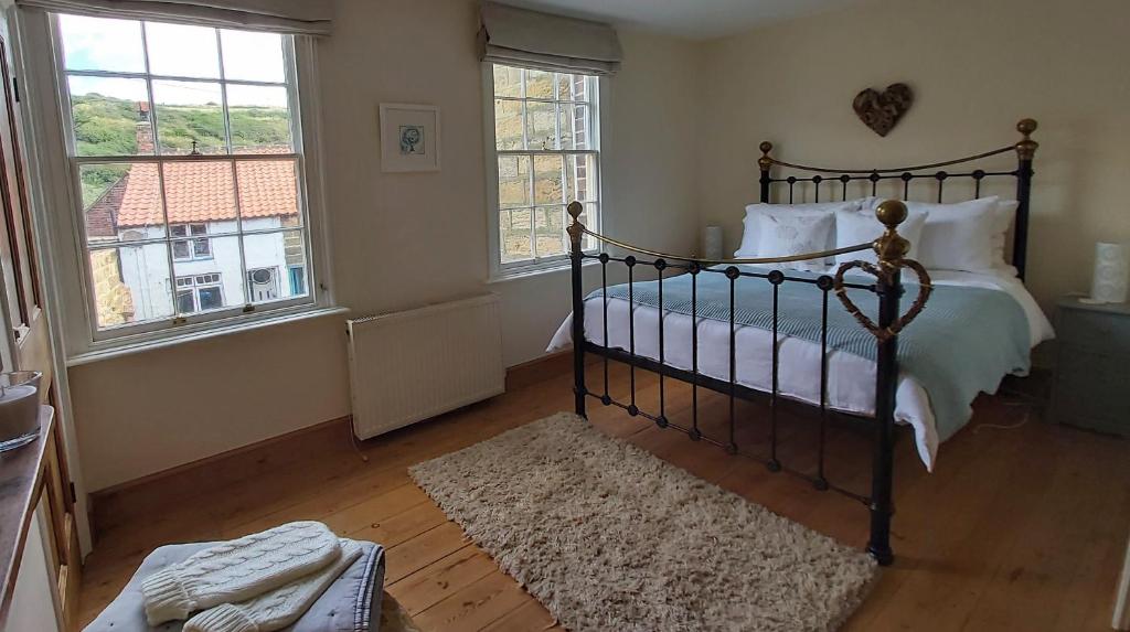 斯泰兹Dunsley Cottage的一间卧室设有一张床和两个窗户。