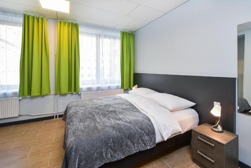 塔林City Yard Inn Hotel的一间卧室配有一张带绿色窗帘的大床