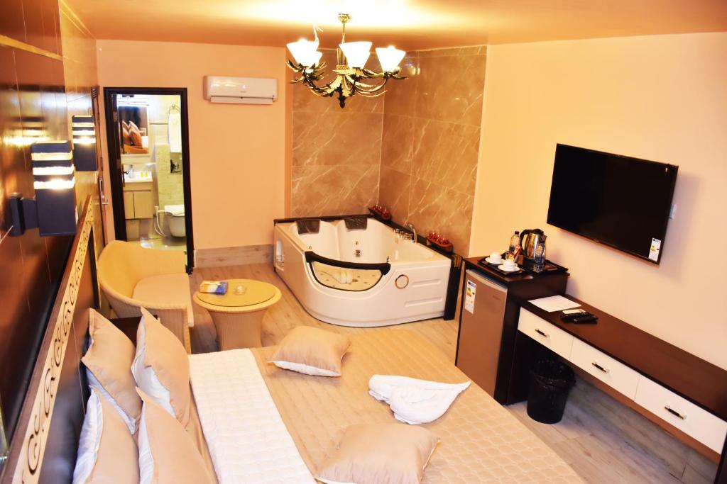 亚喀巴Al-Naher Al-Khaled Hotel的一间带浴缸的浴室和一台电视。