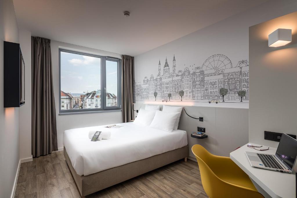 布达佩斯B&B Hotel Budapest City的酒店客房配有一张床、一张书桌和一台笔记本电脑