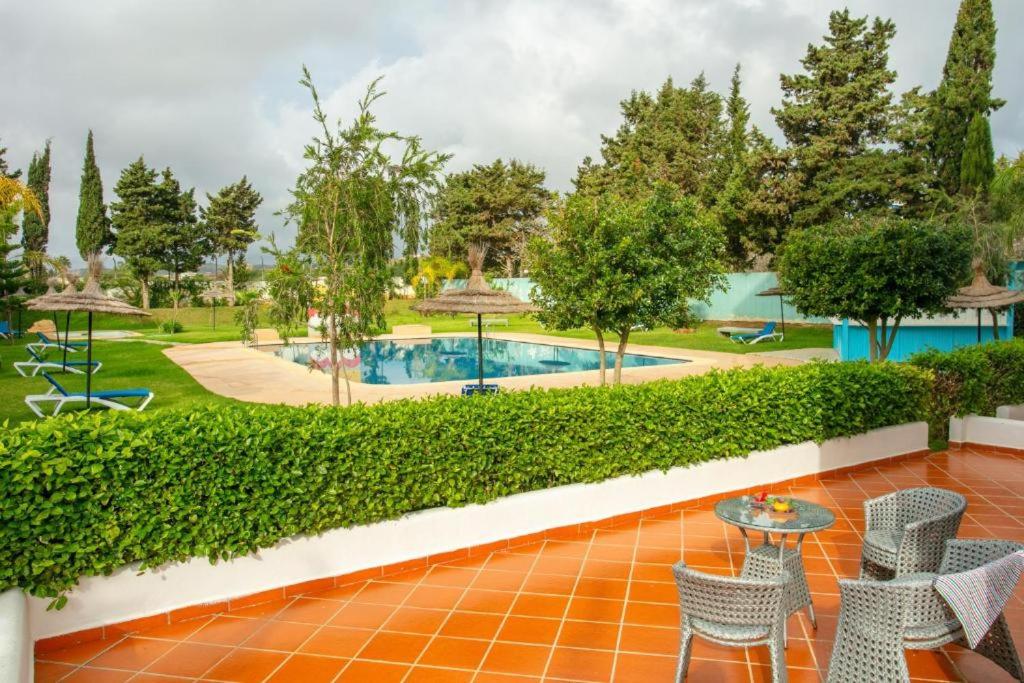 卡博尼格洛Résidence Hôtelière Riviera Beach的一个带桌椅的庭院和一个游泳池