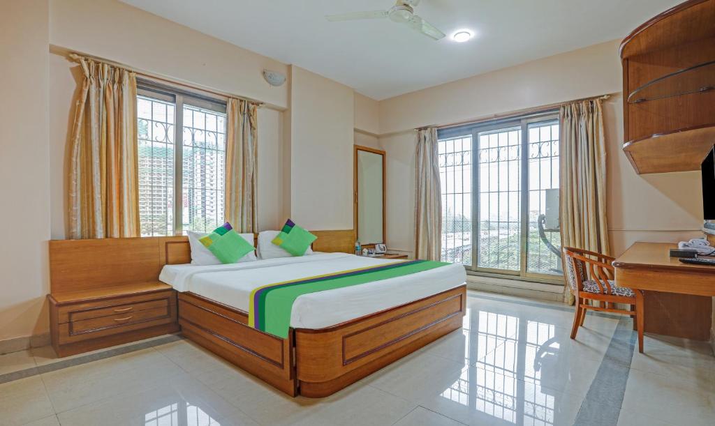 孟买Treebo Trend Welcome Apartments的卧室配有一张床、一张书桌和窗户。