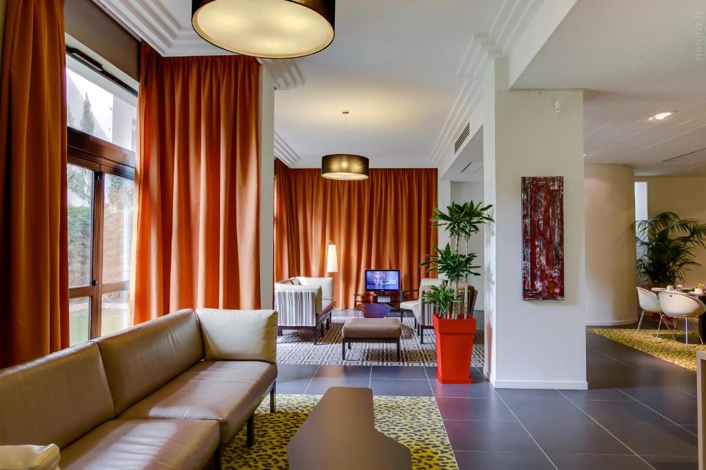 图卢兹Privilège Appart Hôtel Saint Exupéry的带沙发和橙色窗帘的客厅
