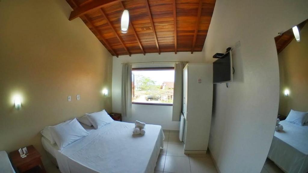 特林达德Pousada Villa Maritima的卧室配有白色的床和窗户。