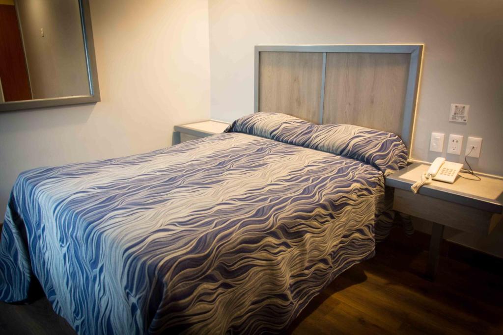 墨西哥城Hotel Antas的一间卧室配有一张床,书桌上配有一部电话