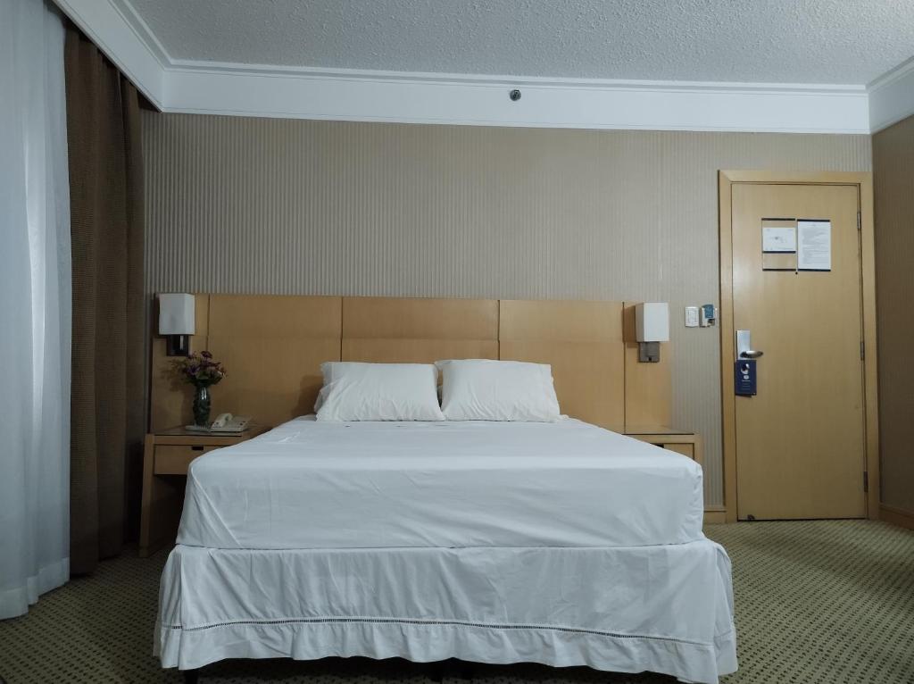 瓜鲁柳斯Flat Guarulhos的一间卧室配有一张带白色床单的大床
