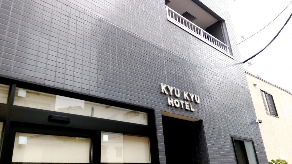 东京KYU KYU HOTEL的一座黑色的建筑,上面写着“新酒店”