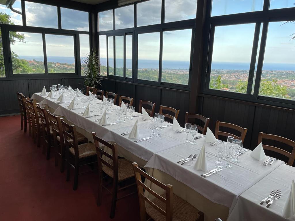 加里Il noceto dell'Etna的窗户间配有一张长桌子和白色的桌椅