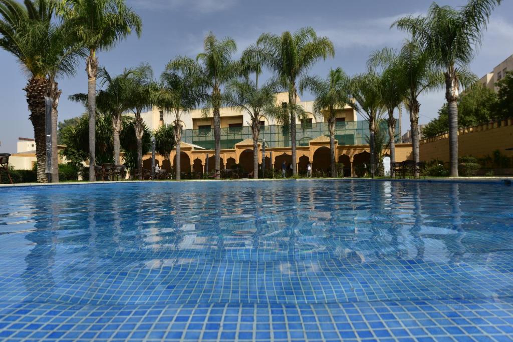 非斯Hôtel Fès Inn & SPA的一座楼前棕榈树游泳池