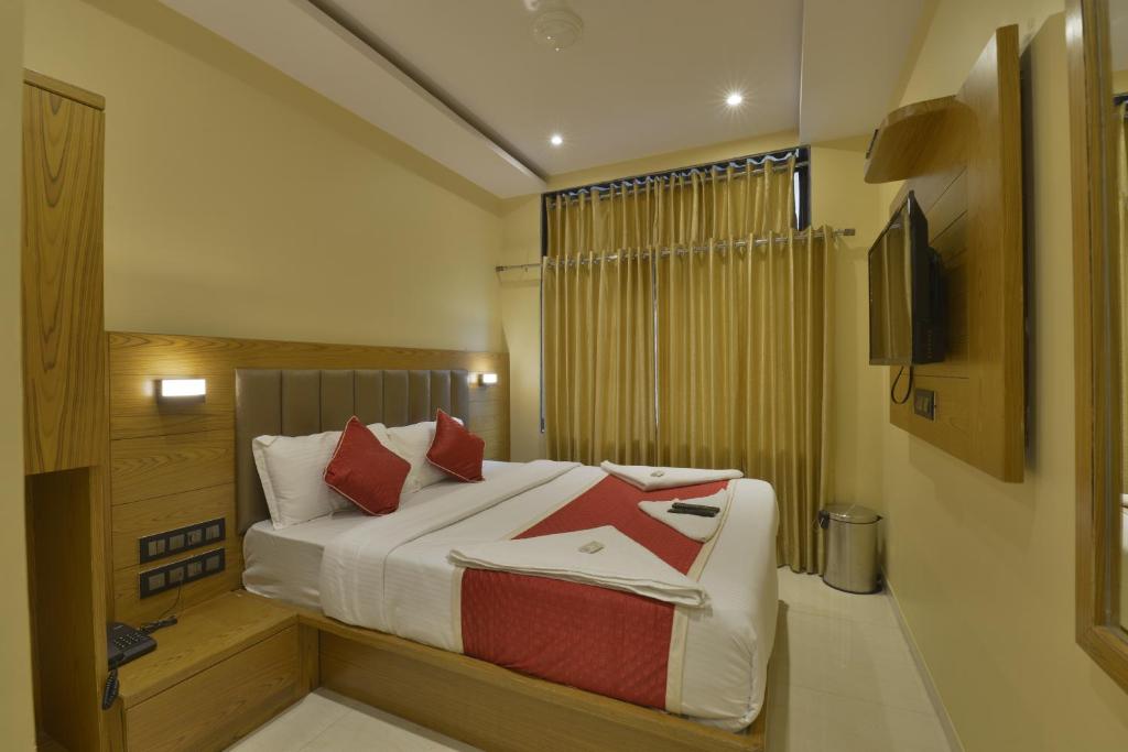 孟买Hotel Residency Park的一间卧室配有一张带红色枕头的床和电视。