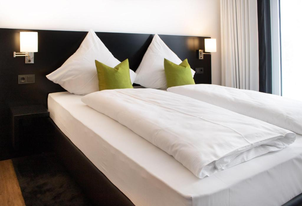杜德尔斯塔特DUD Hotel by WMM Hotels的卧室配有带绿色枕头的白色床