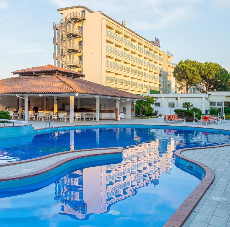 米兰马瑞提那阿德里亚酒店的酒店游泳池的背景是一座建筑