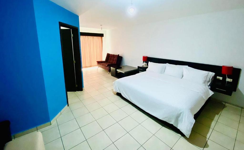 瓜达拉哈拉Hotel Suites del Real的卧室配有白色的床和蓝色的墙壁
