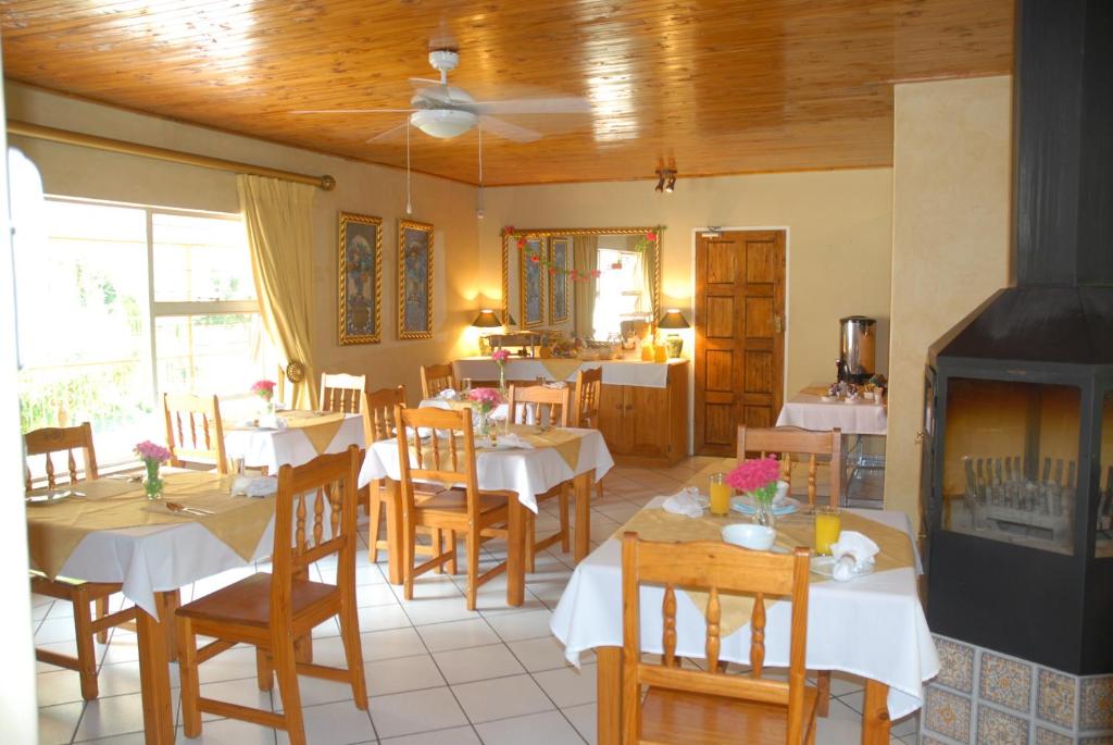 比勒陀利亚紫橄榄宾馆的用餐室配有白色的桌子和木椅
