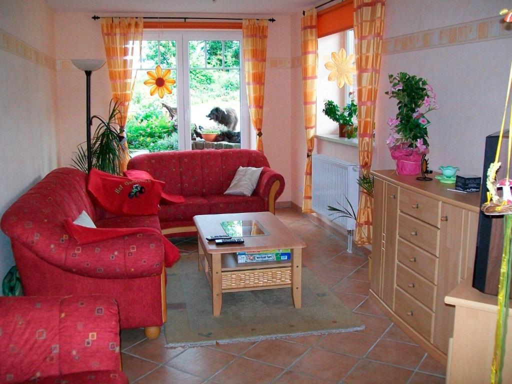 Hanerau-HademarschenFeWo Mareike的客厅配有2张红色沙发和1张咖啡桌
