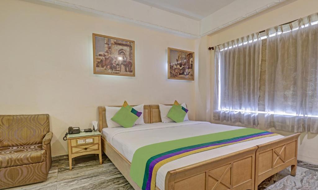 迈索尔Treebo Trend Komfort Suites 3 Km From Mysore Palace的卧室配有床、椅子和窗户。