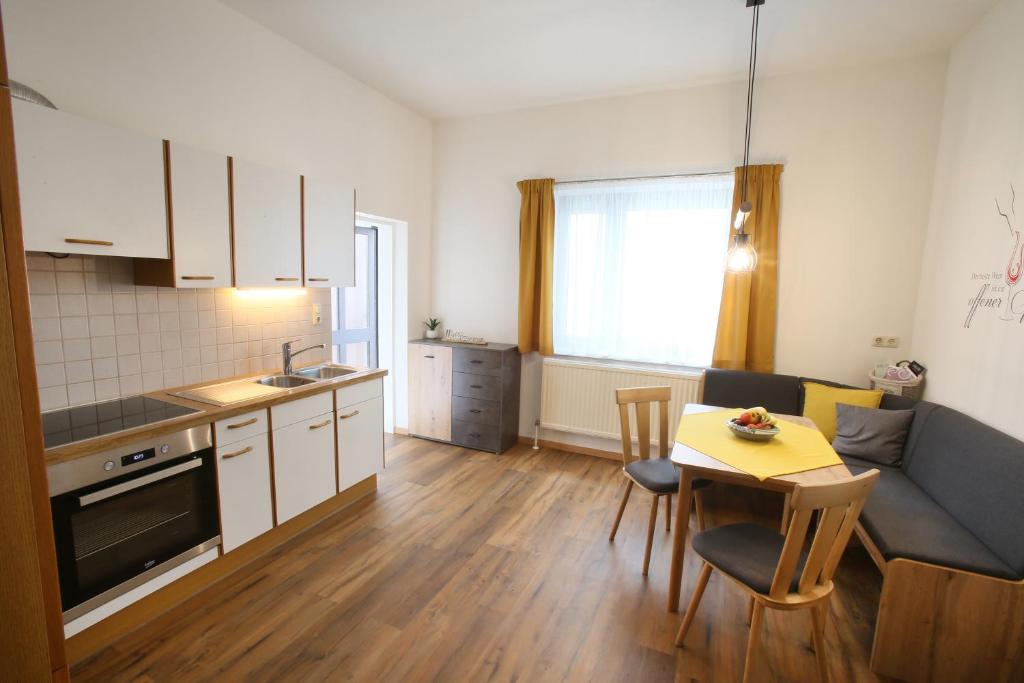 滨湖新锡德尔Appartment Weinbau Müllner的厨房以及带桌子和沙发的客厅。