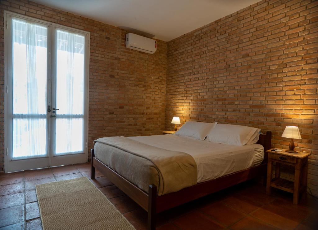 瓜鲁雅Pousada Cocal da Praia的一间卧室设有一张床和砖墙