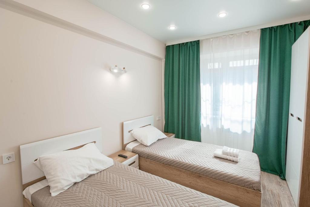 伊尔库茨克Апартаменты Изумруд возле Аэропорта на 2 гостя的一间卧室设有两张床,窗户设有绿色窗帘