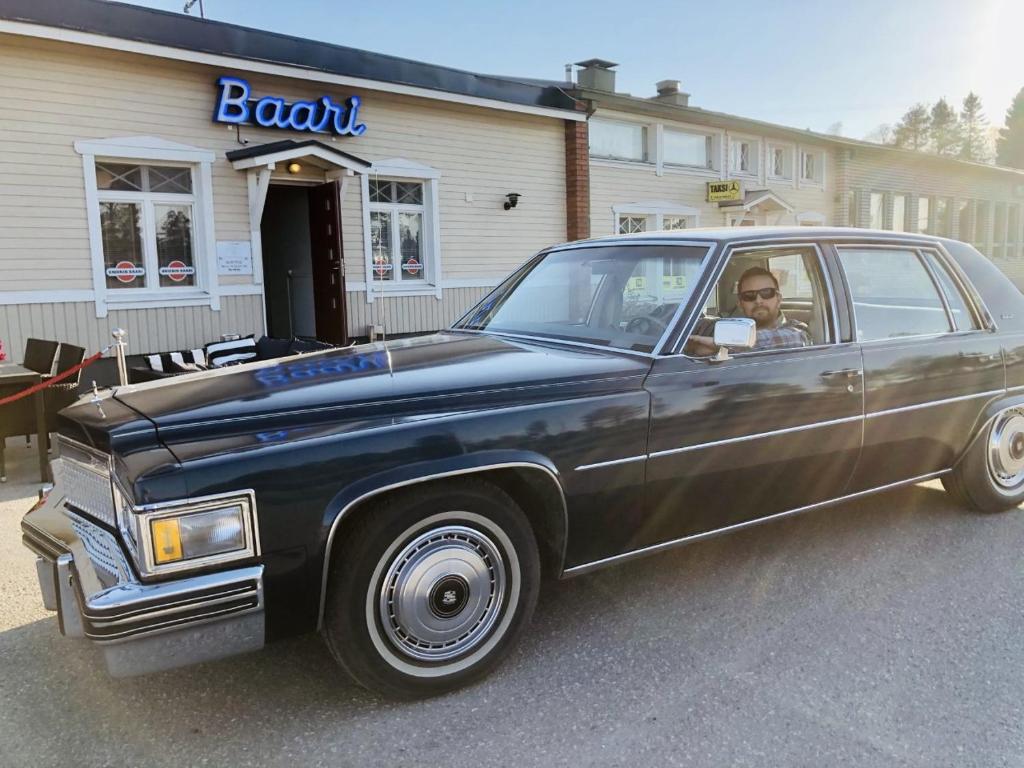 KeminmaaMotel Käpylä的坐在餐馆前驾驶一辆黑色汽车的人