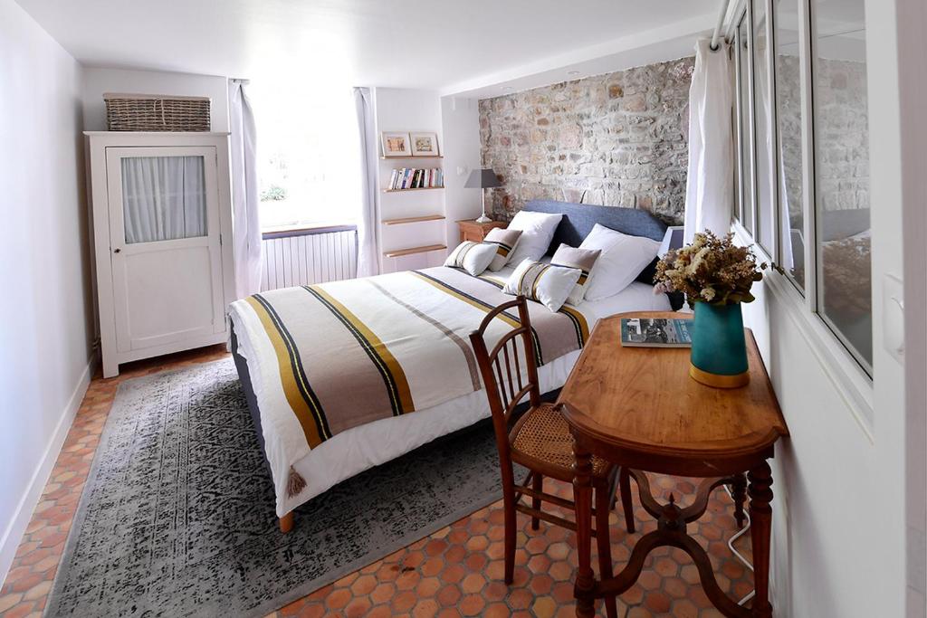 滨海圣佩Le Logis K, le charme au cœur de Saint Pair的一间卧室配有一张床和一张带桌子的木桌。