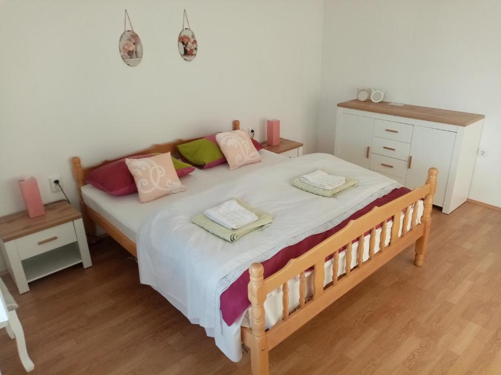塞尼Apartman Petra的一间卧室配有一张大床,配有粉色和绿色的枕头