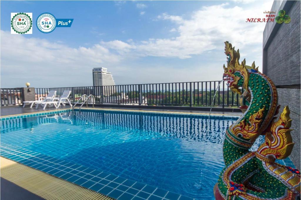 华欣Baan Nilrath Hotel - SHA Extra Plus的一座建筑物旁的游泳池,里面设有龙雕像