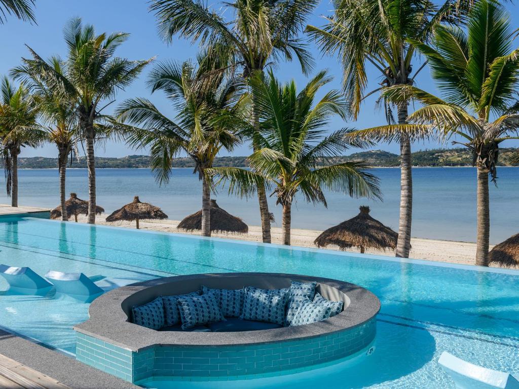 普拉伊拉多比莱尼San Martinho Hotel的一个带海滩和棕榈树的度假游泳池